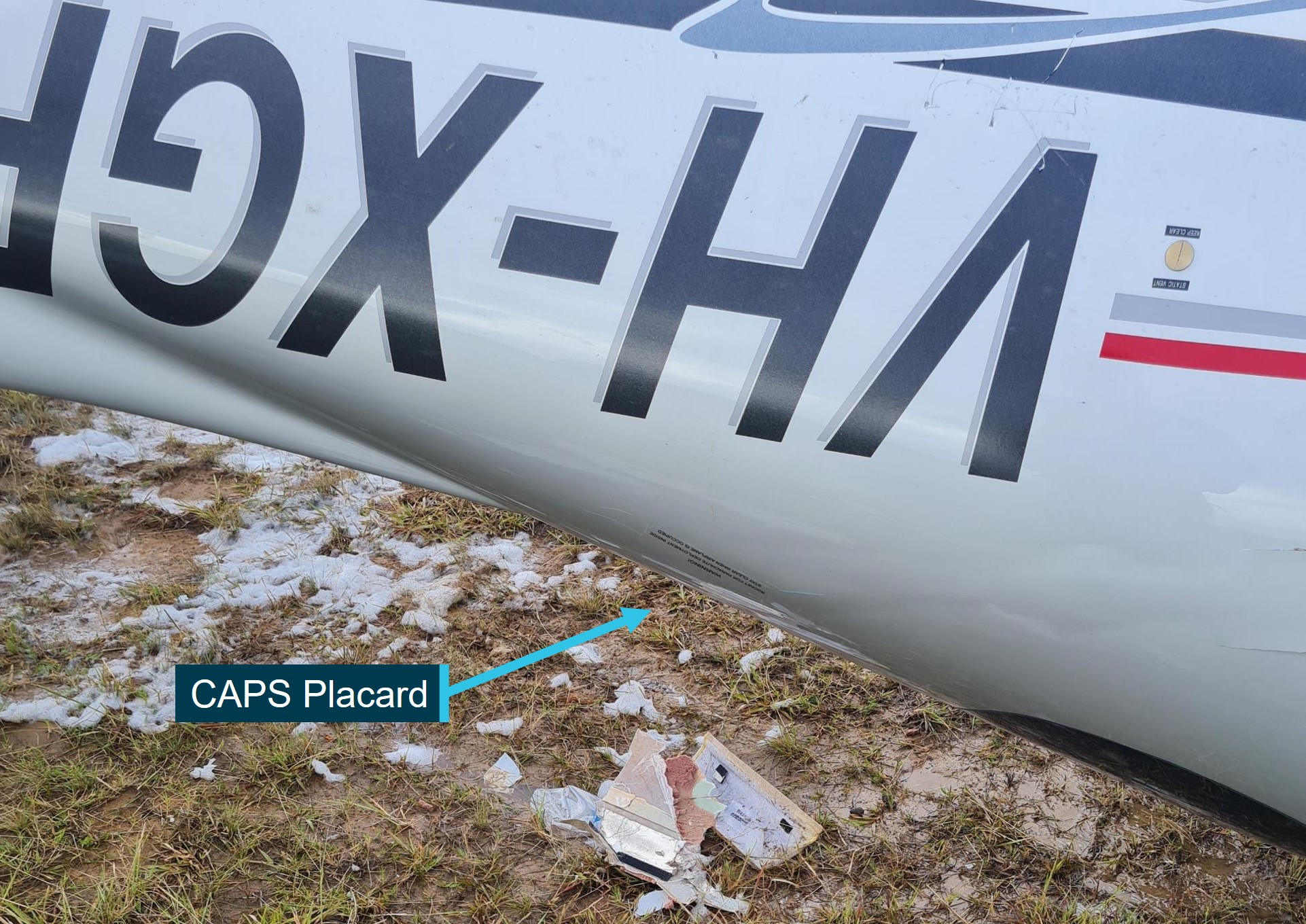 Figure&nbsp;7: Wreckage (inverted) at accident site showing CAPS warning placard on left rear fuselage 