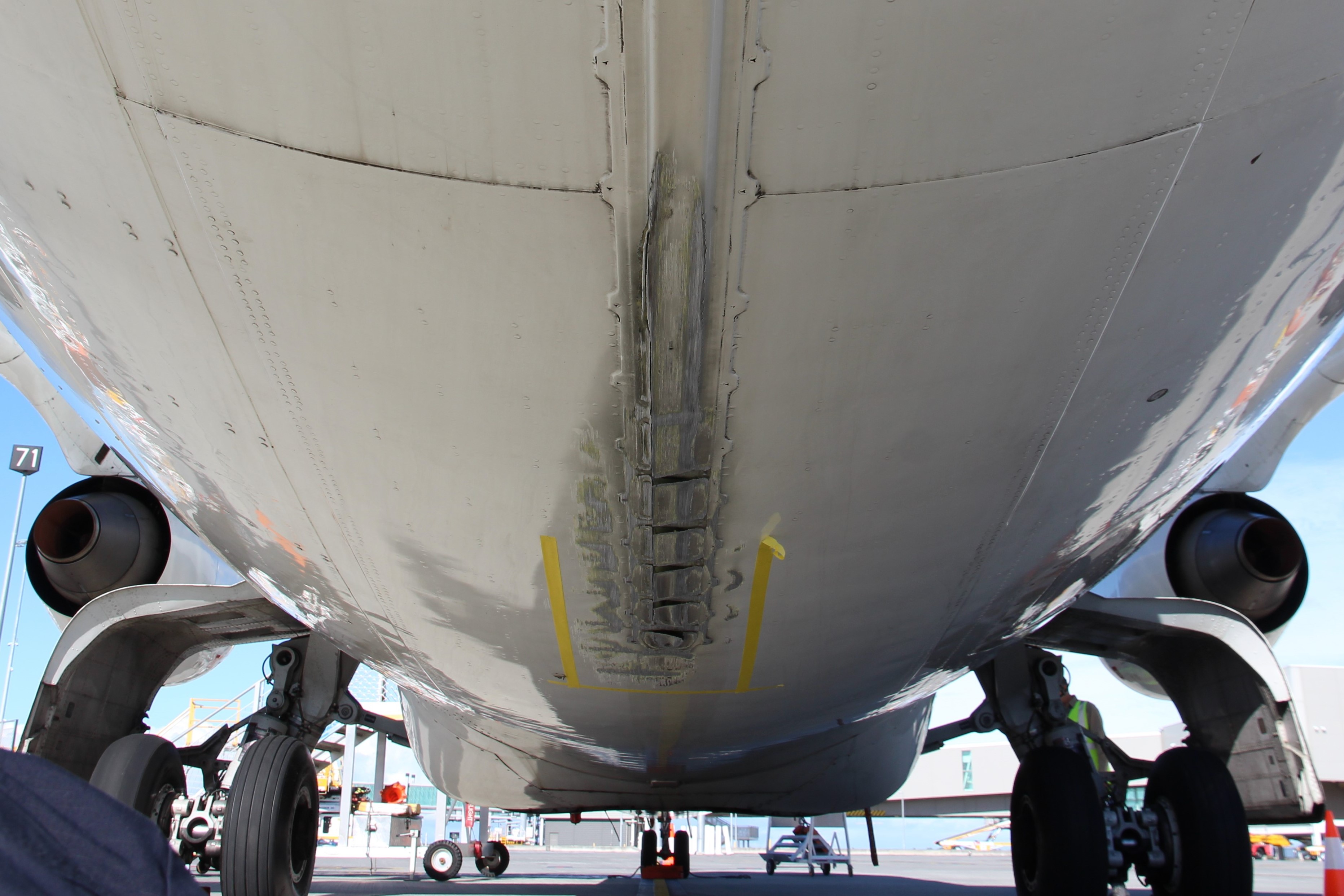 Image shows the underside of VH-SAJ with damage to the tail strike indicator and surrounding panels.