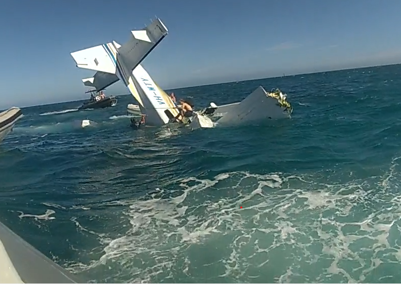 An image of the crashed C208 floatplane registered VH-WTY. The aircraft is partially submerged in the water, with only the tail section visible. 
