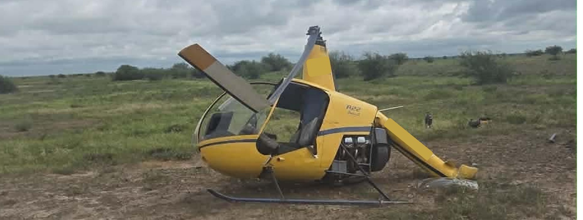 Robinson R22 helicopter post accident, image shows damage to the helicopter's main rotor blade windscreen and tail boom
