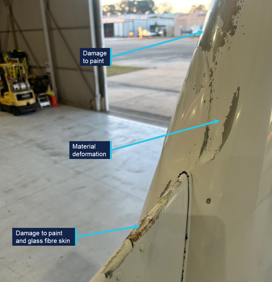 A close-up photograph of VH-EEL's empennage, showing paint damage, material deformation and damage to the glass fibre skin.