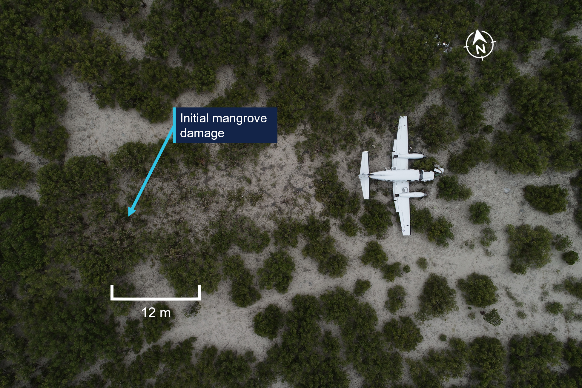 Aerial photograph showing aircraft location after impact, with a blue label indicating "Initial mangrove damage" pointing to a specific area.