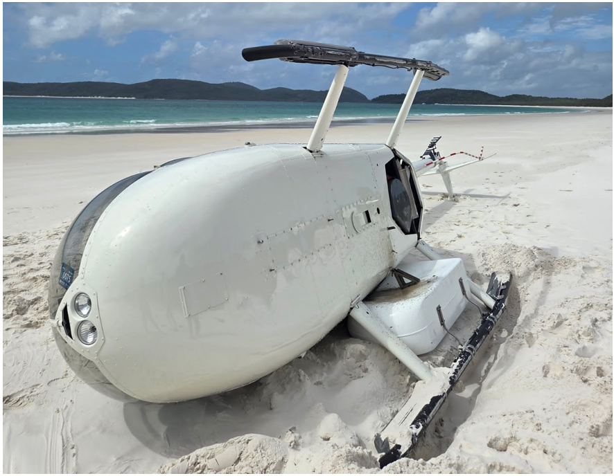 Occurrence R44 helicopter laying on its right side on the sand.