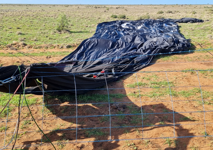 Balloon envelope at rest across the barbed wire fence