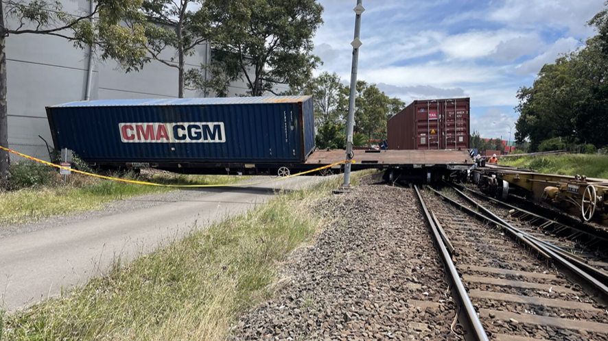 View of a wagon at right angles to track that is touching a building adjacent to rail corridor at accident site Port Botany.
