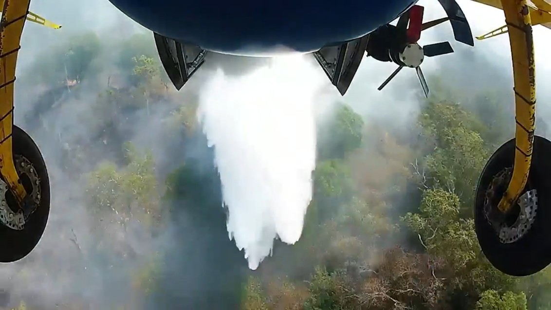 A firefighting aircraft dropping water on a bushfire.