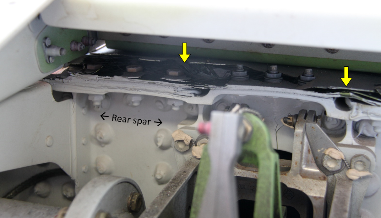 Figure 9: Cracking and delamination of the upper skin on the horizontal stabiliser at the rear spar. View looking forward at the rear face of the rear spar. Damage identified by yellow arrows