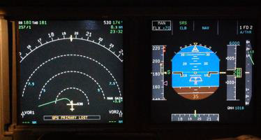 Figure 3: Photograph of an exemplar ND and the primary flight display during a simulated recreation of the flight scenario. Note the GPS PRIMARY LOST message (in yellow) at the bottom-left of the photograph and the green tracking line emanating from the white aircraft depiction at the centre of that representation