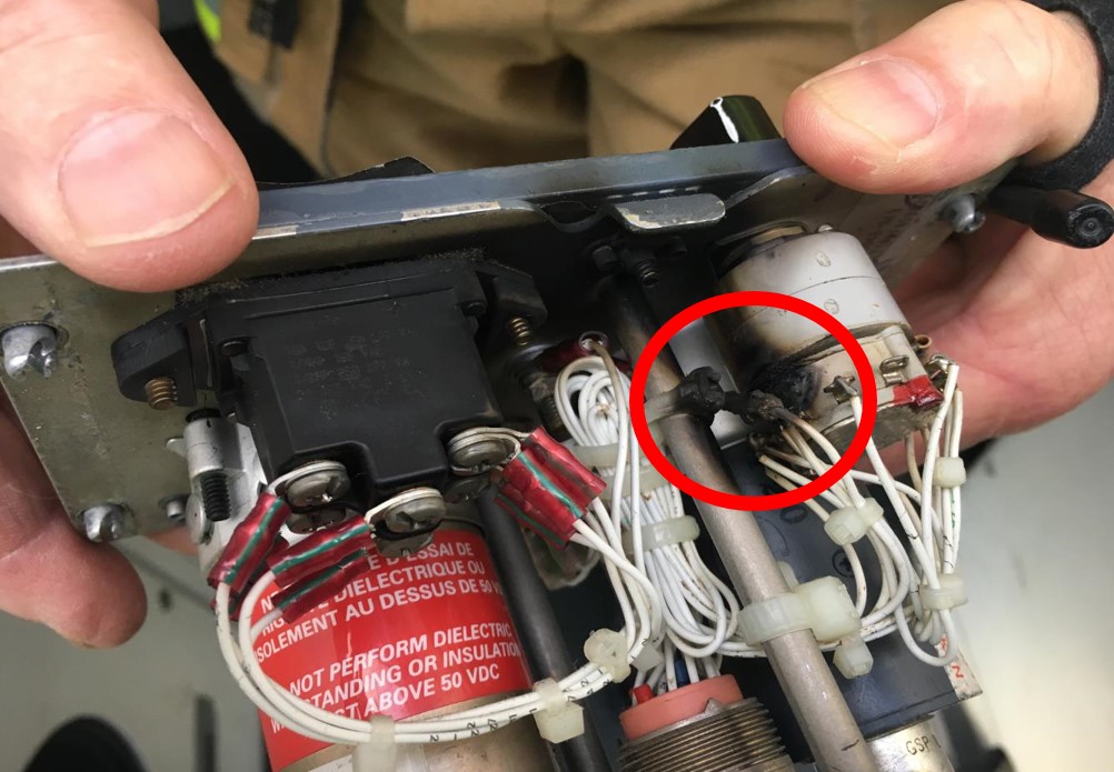 Figure 1: Burnt potentiometer in the aileron/rudder trim control panel (circled in red)