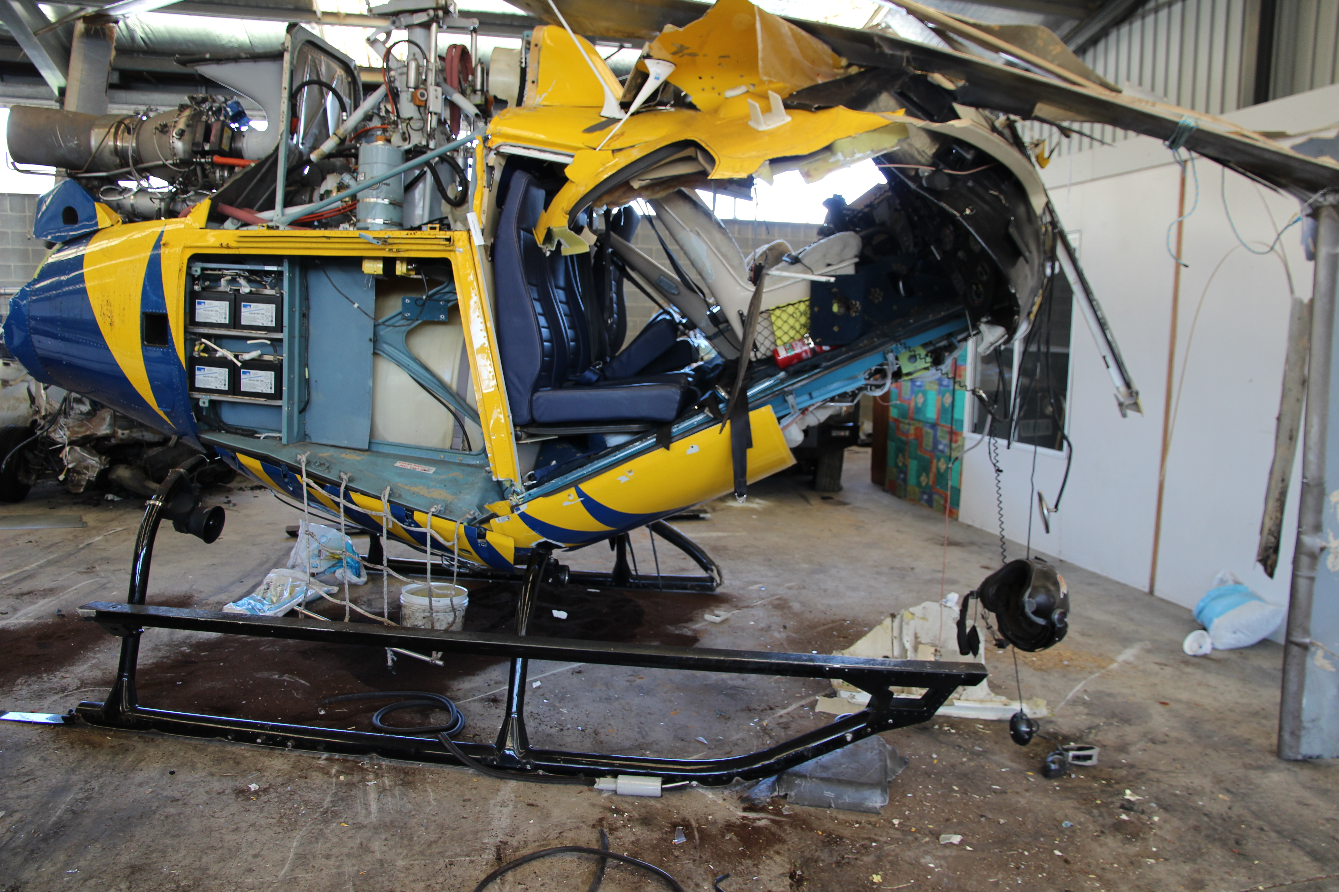 Figure 2: Damage to the helicopter showing significant impact damage to the cockpit area and left landing skid tip, consistent with a left nose-down attitude on impact.