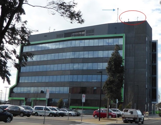 Figure&nbsp;1: Hume City Council building showing the existing antennas (circled in red) and the (then) proposed radio mast (indicated with a blue arrow). Source: ATSB.