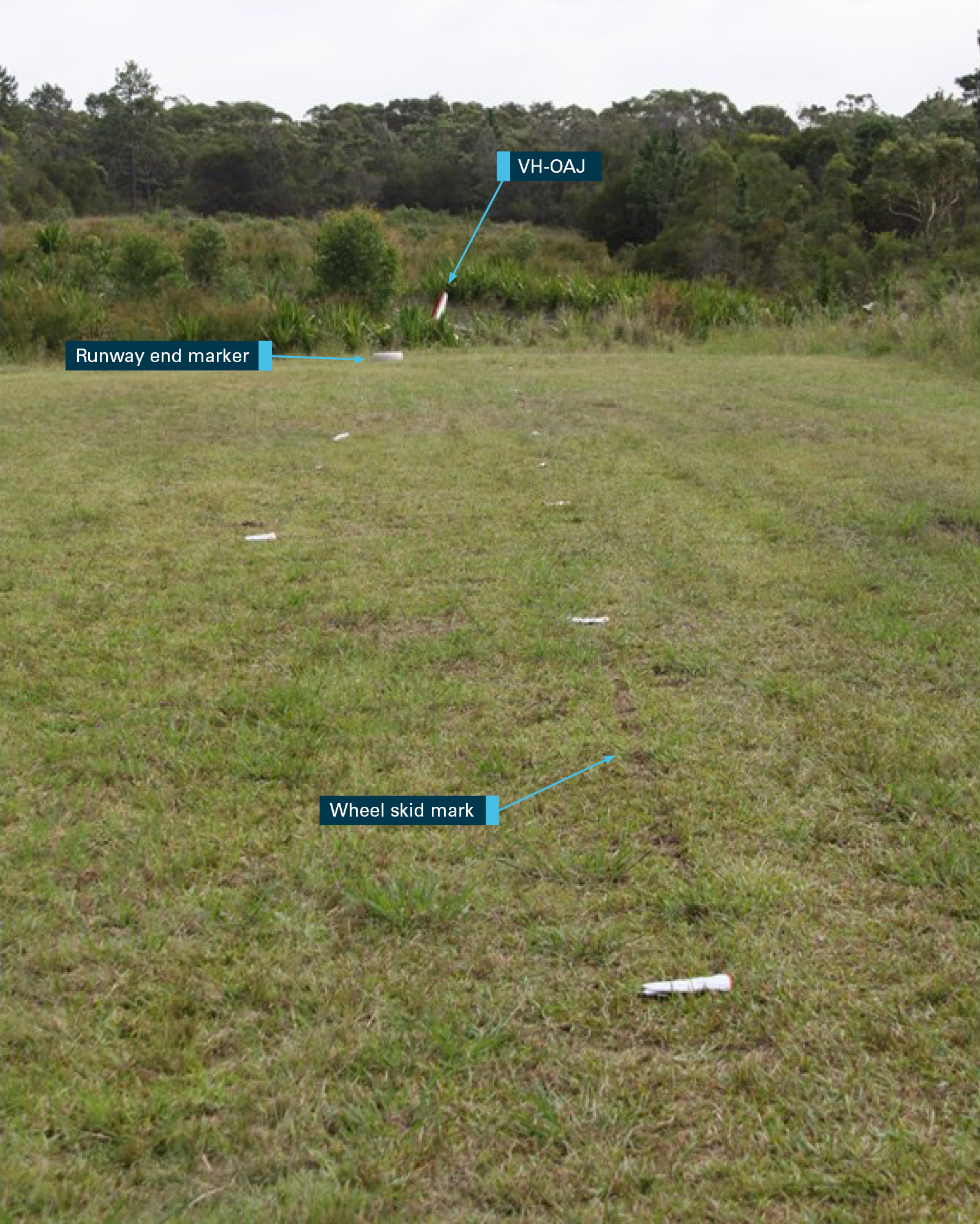 Figure 3: Northern end of runway 35. Marks in the surface of the runway consistent with wheel skid and the tail of VH‑OAJ visible in the background. The white markers indicate the extent of the identified wheel skid marks. Source: ATSB