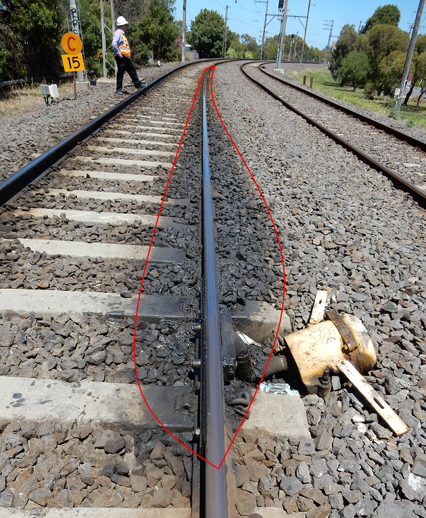 Figure 15: Rail lubricator for the Rushall curve Up track and grease plume. This image shows the rail lubricator for the Rushall curve, located on tangent track. The grease plume indicates that much of the lubricant has been flung off the wheel and deposited on the track. Note that the right-hand curve in the distance is an intervening (opposite) curve, and is not the one intended to be served by this lubricator. The left-hand Rushall curve is further in the distance and not shown on this photograph.<br />
Source: Chief Investigator Transport Safety (Vic)