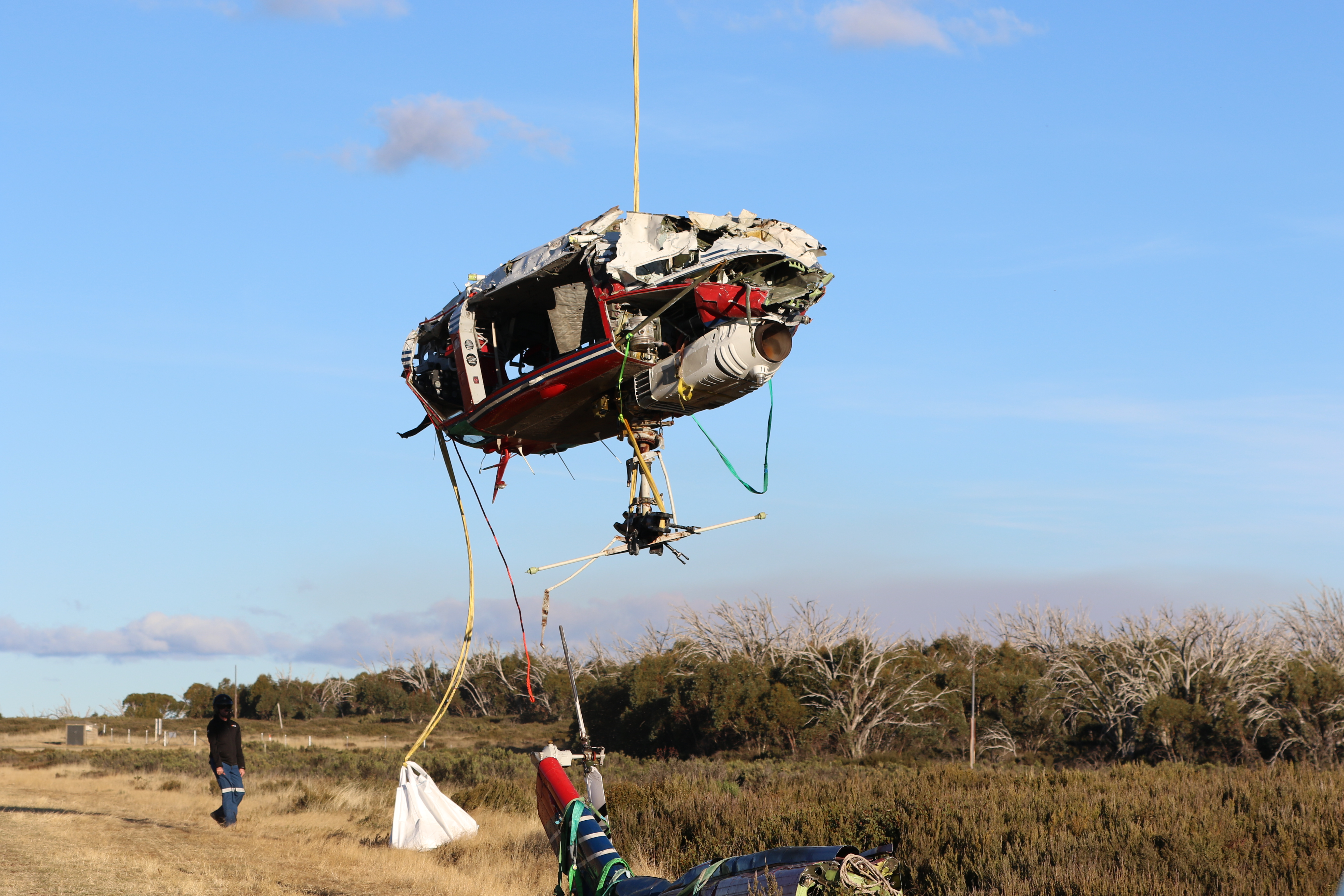 Figure 6: Helicopter wreckage lifted to Cabramurra aircraft landing area. Wreckage of VH-HUE being lowered by an s-61 ‘Sea-King’ to Cabramurra ALA for transfer to a secure hangar. Source: ATSB