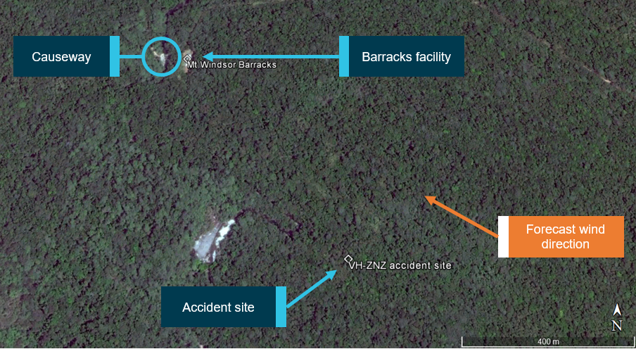 Figure 4: Accident site relative to barracks facility and causeway. Forecast wind direction indicating the accident site was located about 500–600 m upwind of the barracks facility and causeway.  Source: Google earth, annotated by ATSB