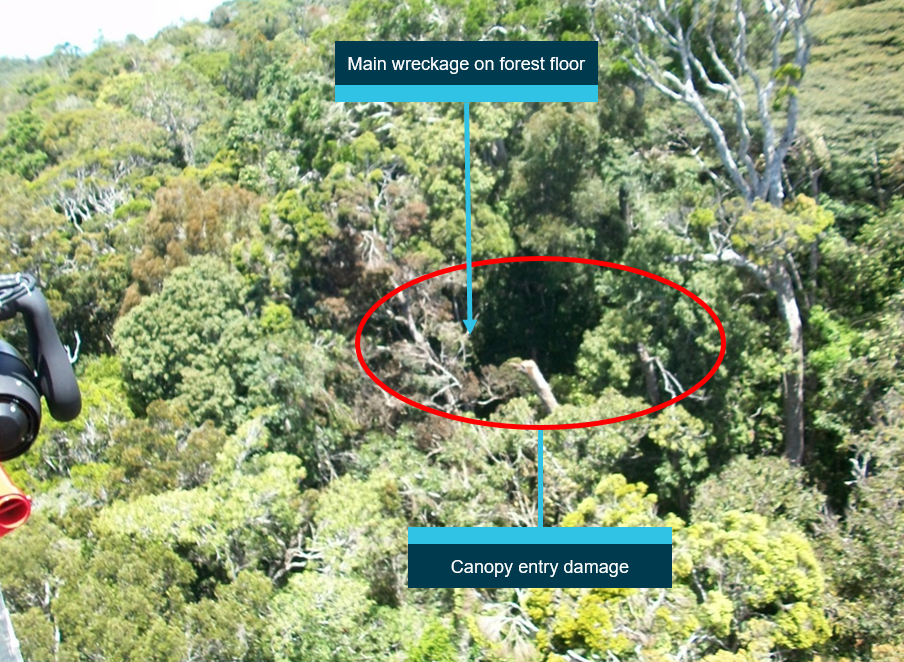 Figure 5: Approach to canopy entry directly above wreckage site. Rescue helicopter view of the damaged canopy. Main body of the helicopter is located on the forest floor, about 100 ft directly below the canopy damage.  Source: Search and rescue helicopter service (courtesy Queensland Police Service), annotated by ATSB