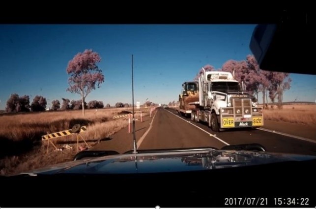 Figure 10: Dash camera footage from a private vehicle. The image shows a prime mover and low-loader carrying a front-end loader as it approached level crossing ID 2309. The time stamped on the image is 1534:22 on Friday 21 July 2017. Source: private vehicle operator