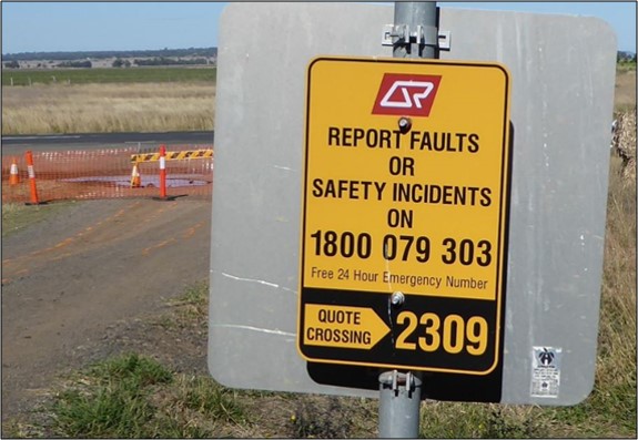 Figure 11: Incident reporting sign at level crossing ID 2309. The image shows the incident reporting sign and the emergency contact number, in place at level crossing ID 2309 on the day of the derailment.<br />
Source: ATSB