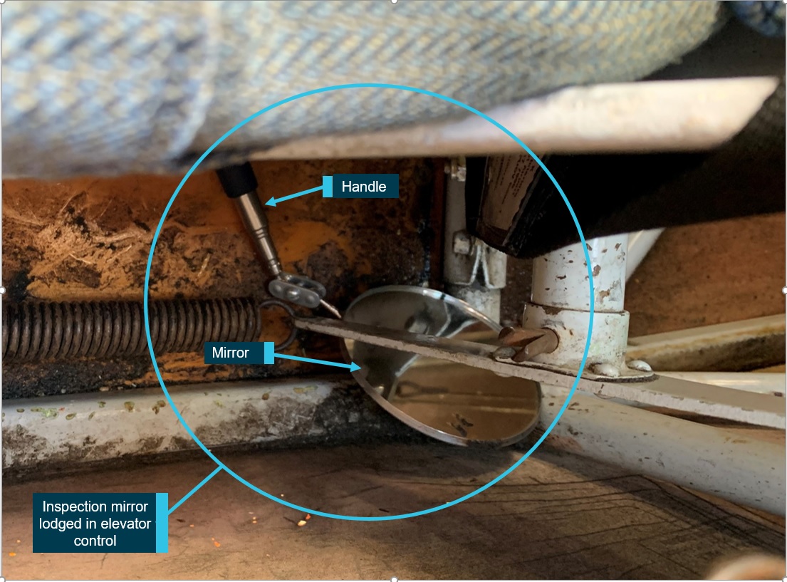 Figure 1: Hand-held inspection mirror lodged in elevator control.<br />
Source: Operator