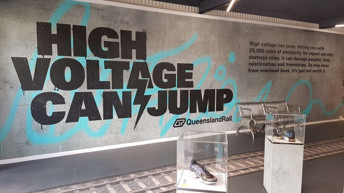 Figure A2: Queensland Rail’s ‘High Voltage Can Jump’ public awareness campaign.
Image of Queensland Rail’s stand at the 2019 Brisbane Exhibition, highlighting the dangers of electrical arc from high voltage OHLE. The campaign was widespread throughout Brisbane, including significant display materials at Brisbane’s Central station.
Source: ATSB