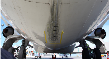 Image shows the underside of a BAE 146 from the rear of the aircraft looking forward, showing the damaged caused by the tail strike to the tail strike indicator and surrounding fuselage skin panels.