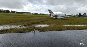 The aircraft in muddy ground off the end of the runway.