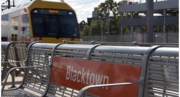 A train passing in the background of a bench at Blacktown Station. Source: Transport for NSW