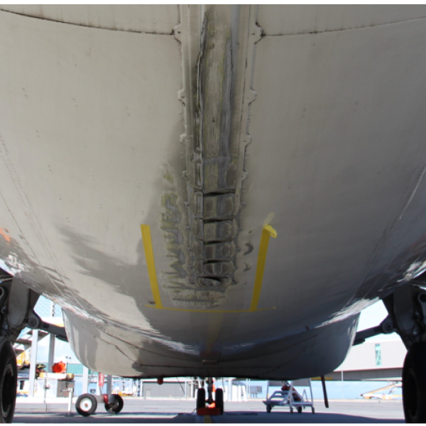 Image shows the underside of a BAE 146 from the rear of the aircraft looking forward, showing the damaged caused by the tail strike to the tail strike indicator and surrounding fuselage skin panels.