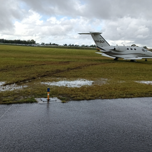 The aircraft in muddy ground off the end of the runway.