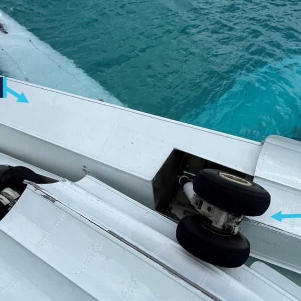 Image of overturned aircraft, post-accident, showing left main gear retracted into the float and right main gear extended.