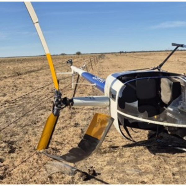 Robinson R22 VH-HGE on its right side with visible damage to the main rotor blades and windshield.
