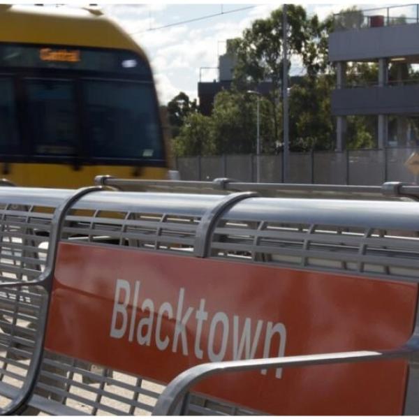 A train passing in the background of a bench at Blacktown Station. Source: Transport for NSW
