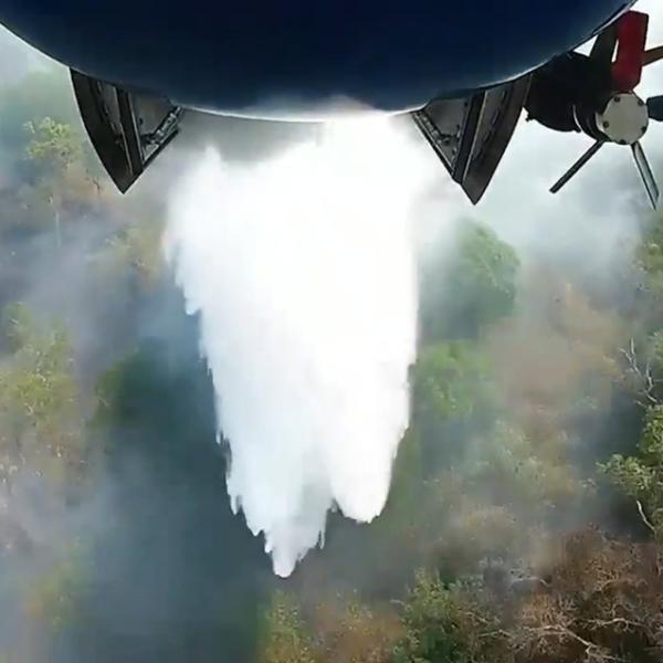 A firefighting aircraft dropping water on a bushfire.