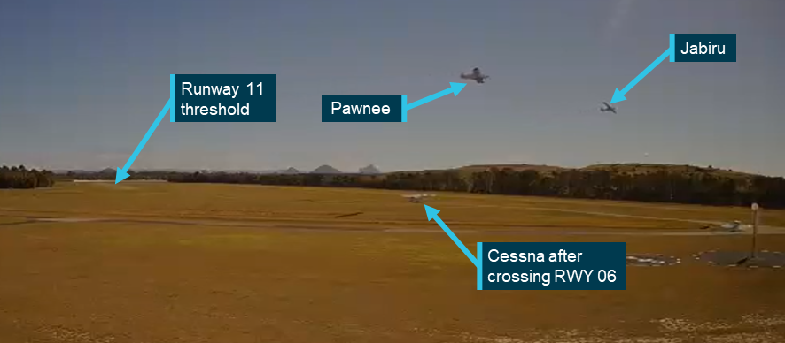 Still image taken from the CCTV camera showing the Pawnee and Jabiru converging with the Cessna on the ground. The position of the runway 11 threshold is indicated with an arrow.