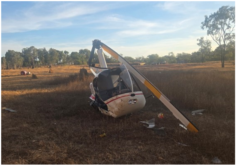 Robinson R22 helicopter in a field. The image shows the windscreen is shattered, tail cone missing and damaged rotor blades.