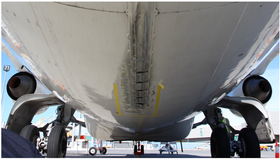Image shows the underside of a BAE 146 from the rear of the aircraft looking forward, showing the damaged caused by the tail strike to the tail strike indicator and surrounding fuselage skin panels.