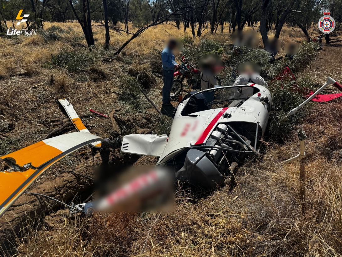 Robinson R22 on its left side in a dry creek bed. The image shows damage to the fuselage and main rotor system. The tail rotor assembly was removed in the accident sequence.
