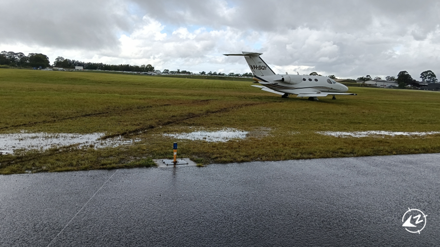 The aircraft in muddy ground off the end of the runway.